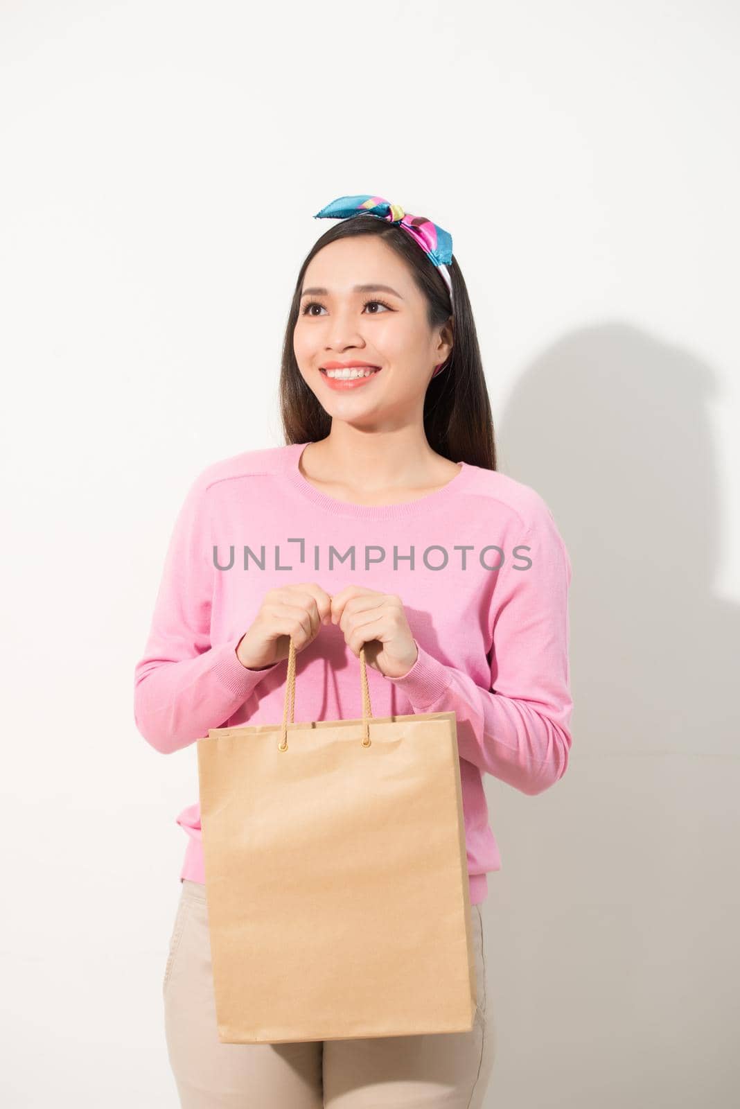 Close up portrait young beautiful attractive girl smiling with brown shopping bag. White background. Copy space. by makidotvn