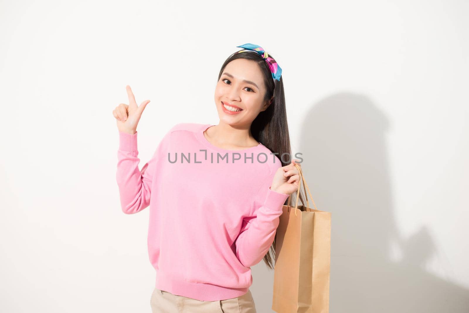 Cheerful young pretty woman raising shopping bags, dancing and looking at camera. Consumerism concept. Isolated front view on white background. by makidotvn