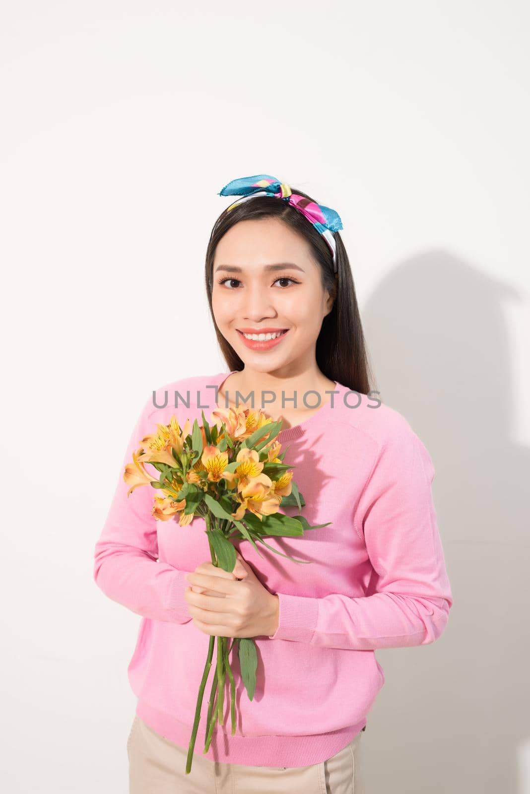 Toothy smiling happy woman holding flower . White background isolated portrait.