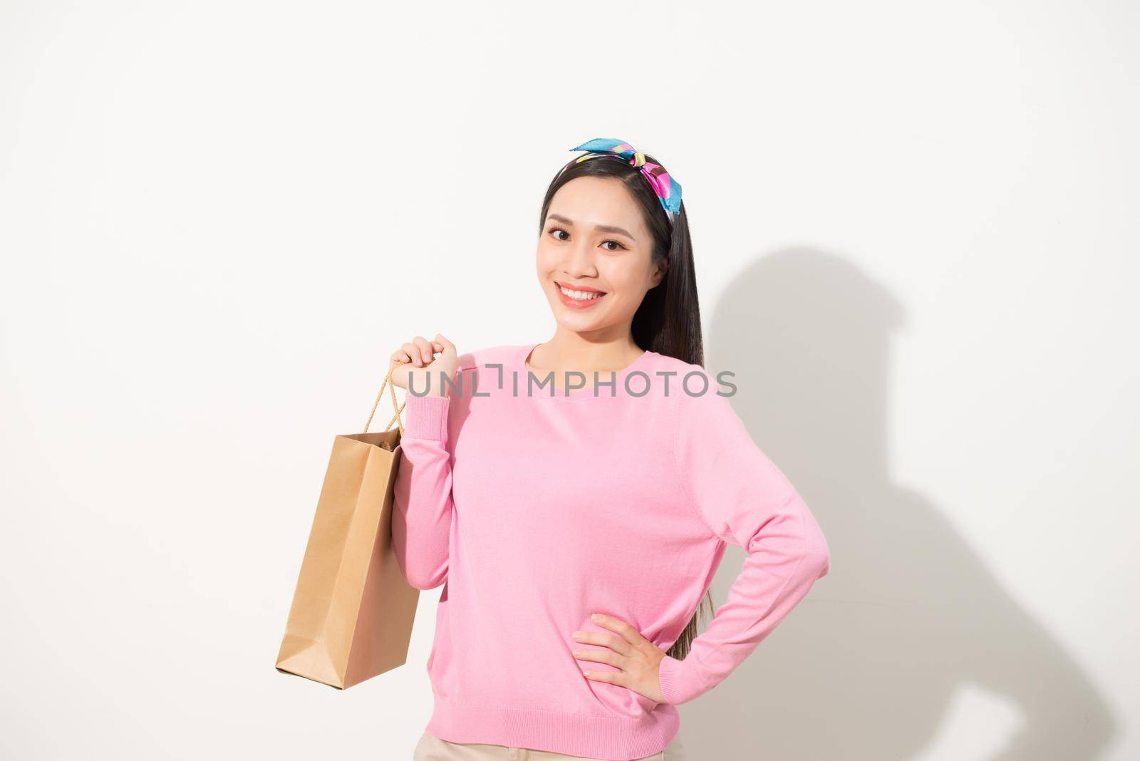 Beautiful young woman (girl) standing and holding a light brown bag, which can be applied to any logo. White background. Portrait in full growth