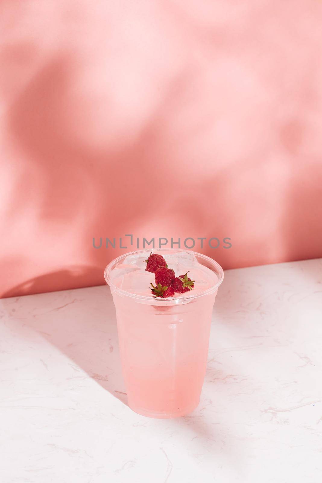 Summer juice with fresh raspberries in a glass on a light background