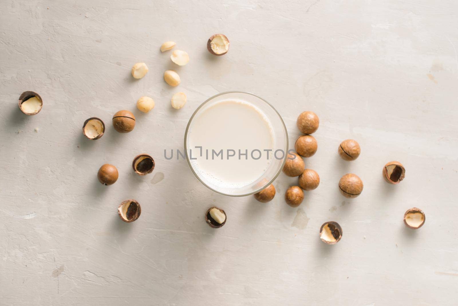 Superfood. Organic macadamia nuts and glass of macadamia milk on stone background. by makidotvn