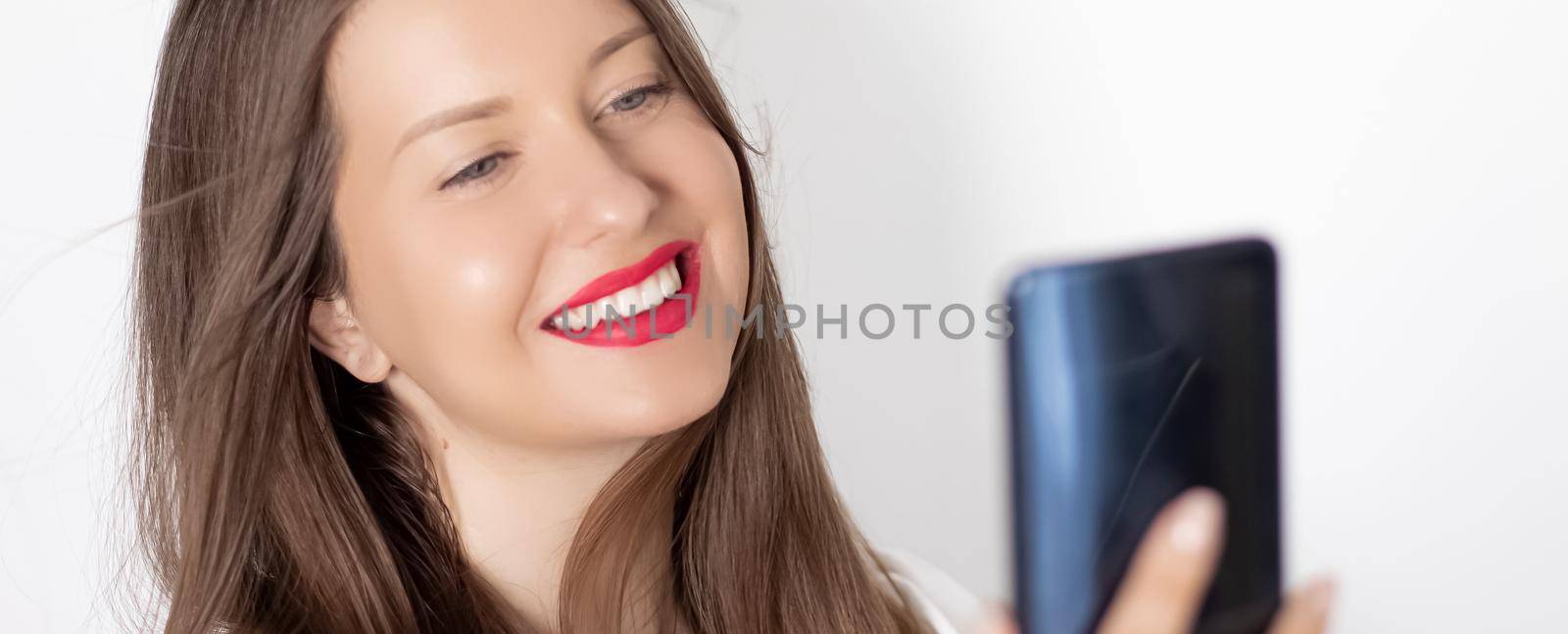 Happy smiling woman with smartphone having video call or taking selfie, portrait on white background. People, technology and communication concept by Anneleven