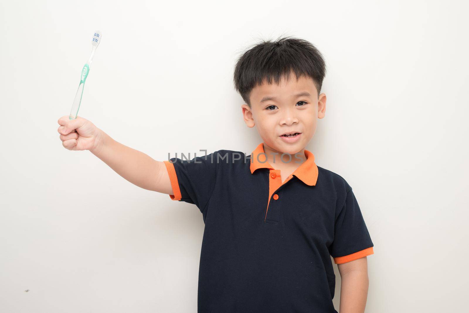 Cheerful little boy holding a tooth brush over white background, Studio portrait of a healthy mixed race boy with a toothbrush isolated. by makidotvn