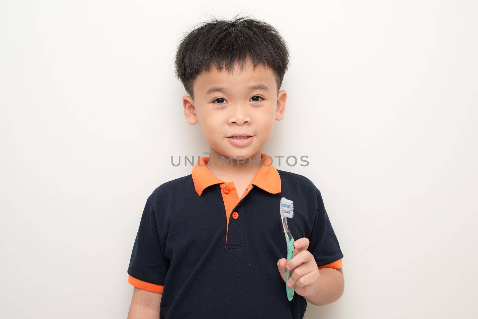 Cheerful little boy holding a tooth brush over white background, Studio portrait of a healthy mixed race boy with a toothbrush isolated.