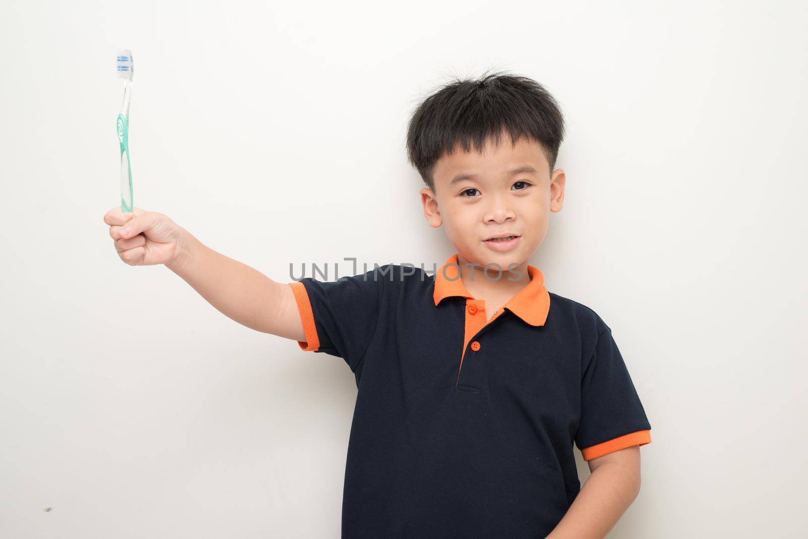 Cheerful little boy holding a tooth brush over white background, Studio portrait of a healthy mixed race boy with a toothbrush isolated. by makidotvn