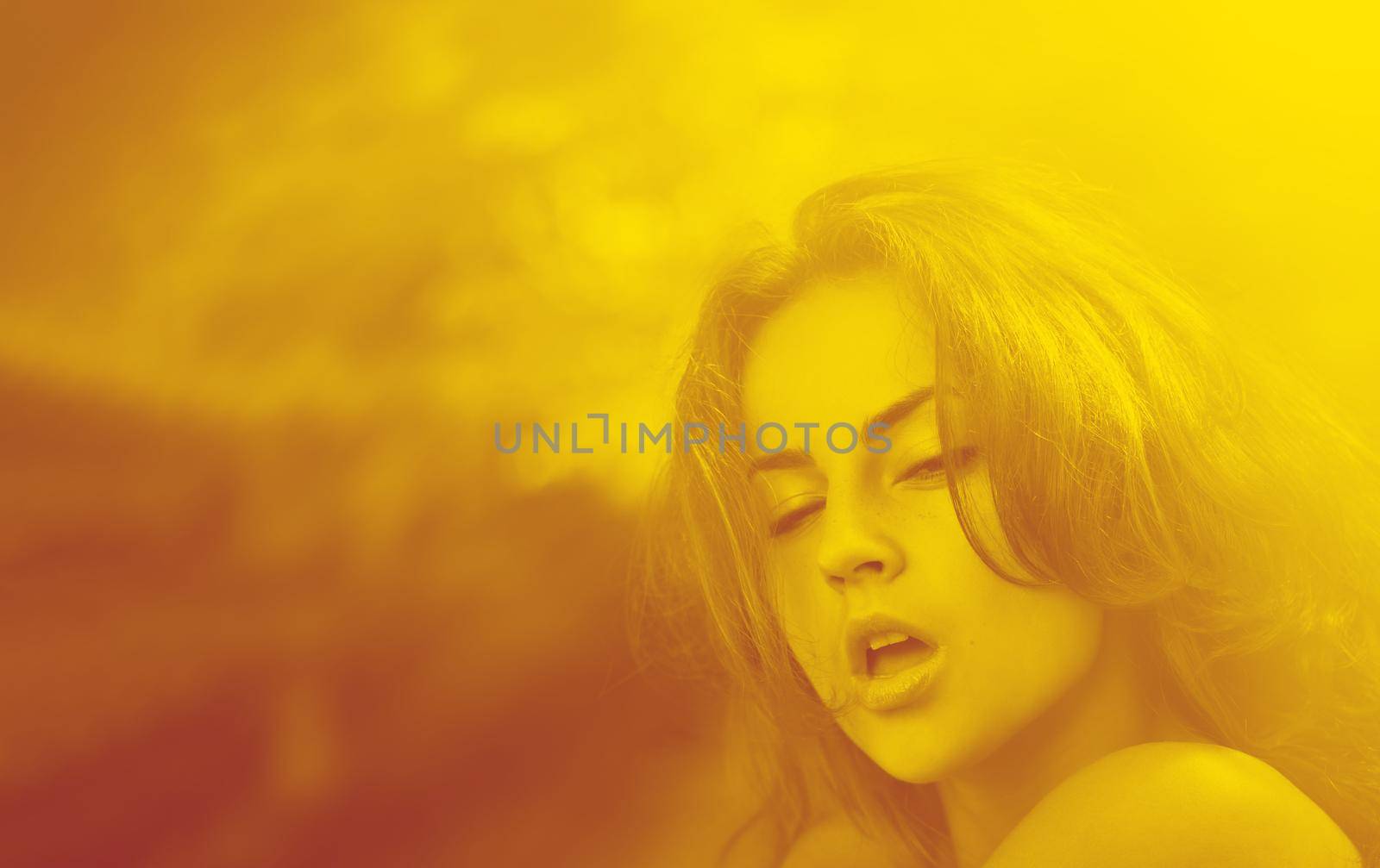 Duotone yellow and red portrait of an emotional young woman against blured nature background of autumn forest.