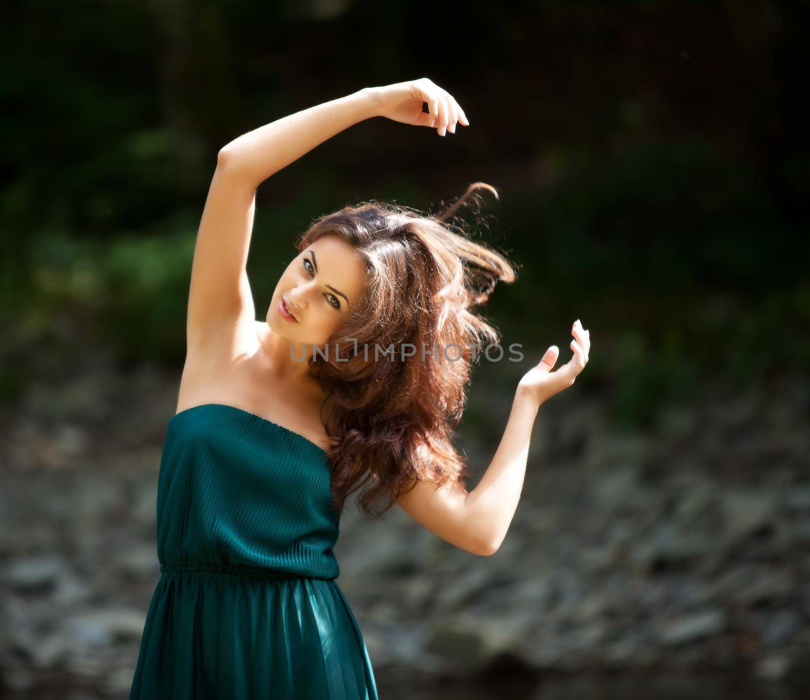 Portrait of a young woman with arms raised against a dark background in motion