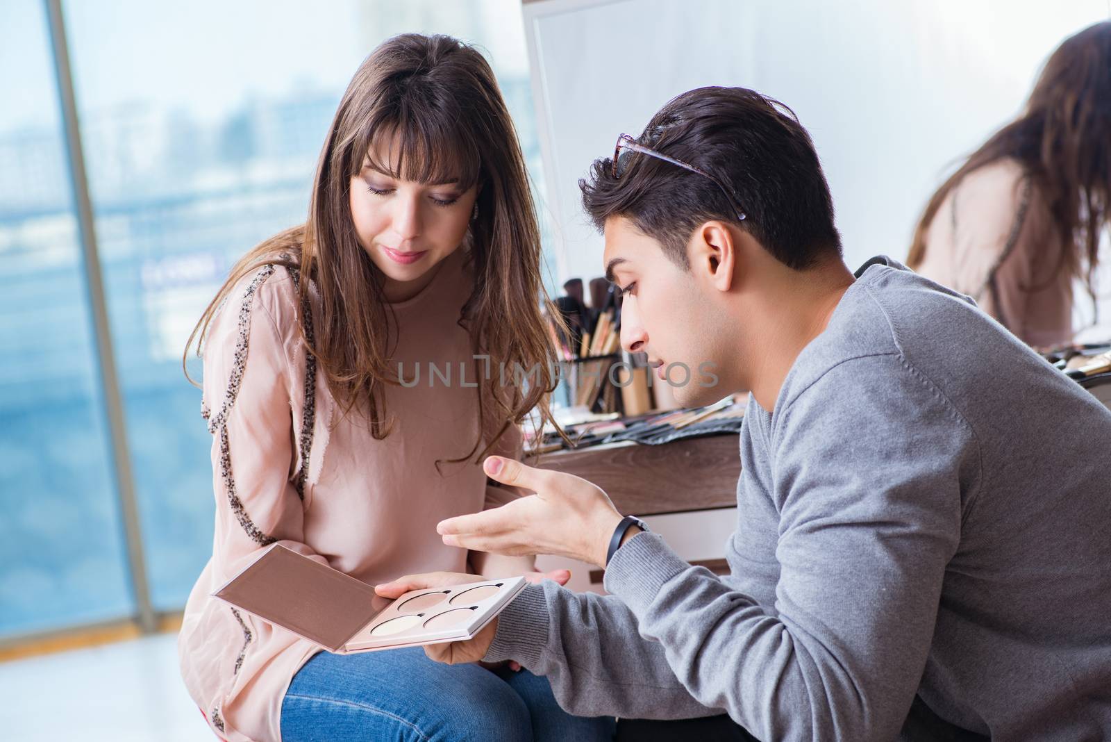 Man doing make-up for cute woman in beauty salon