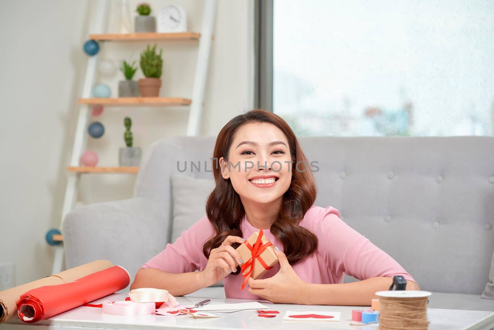 Happy young woman pressing gift box to her chest