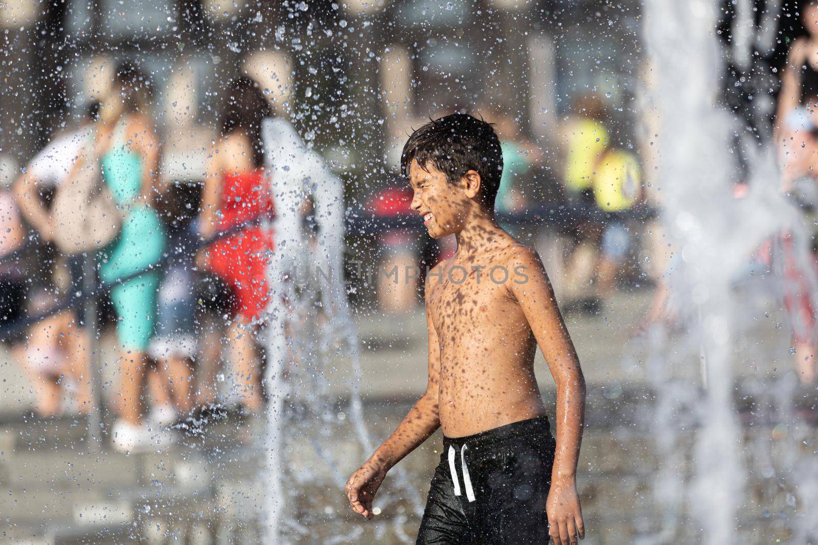 Happy children playing in a water fountain by palinchak