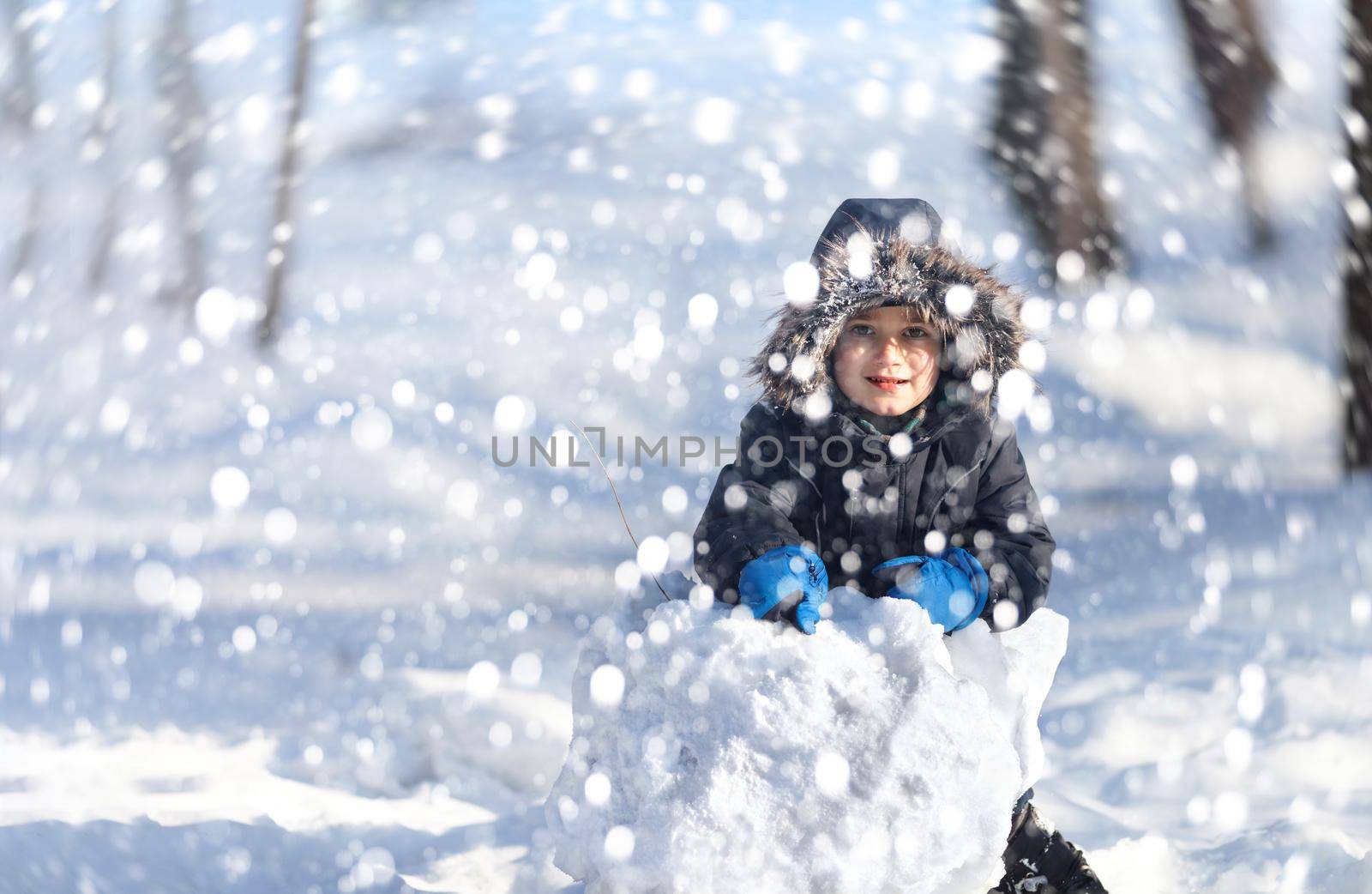 Cute boy playing with snow in the winter park by palinchak