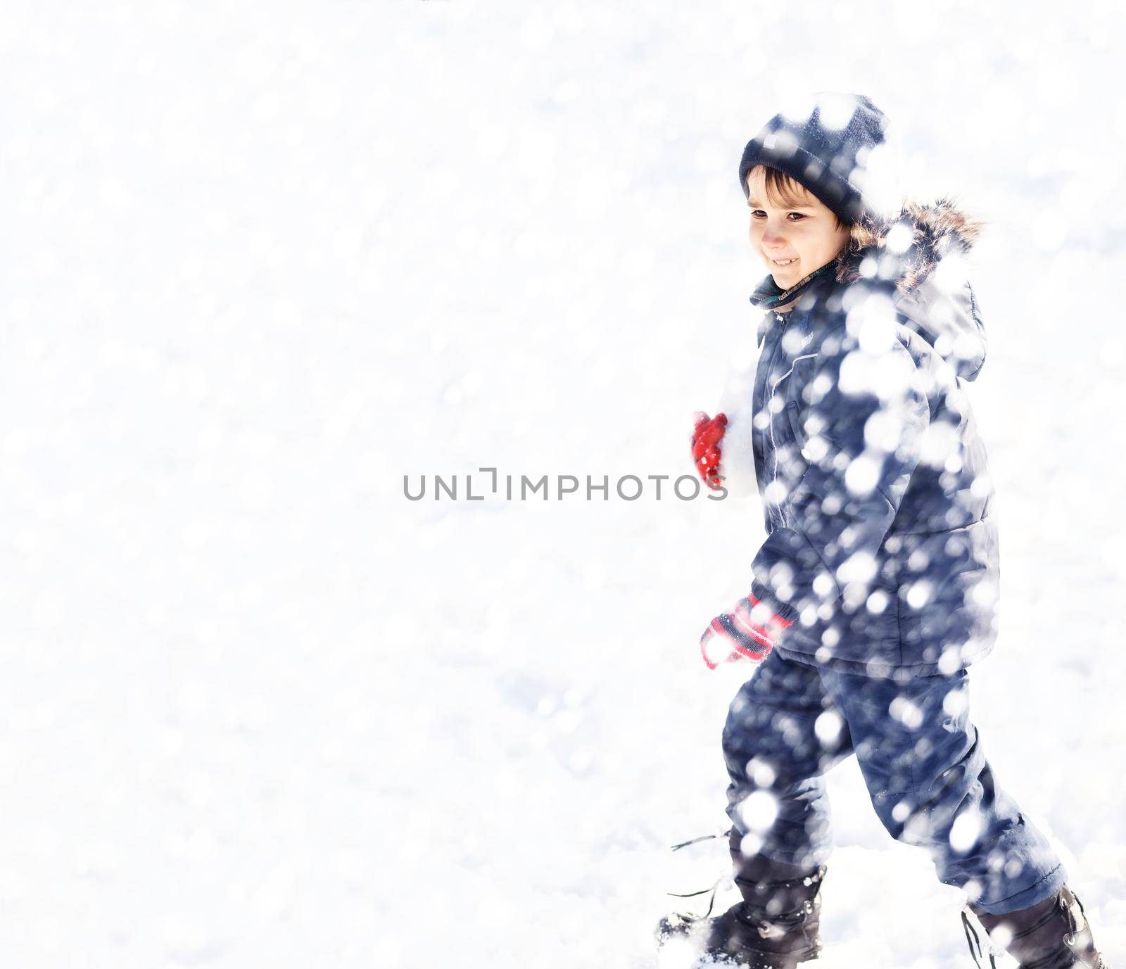 Cute boy playing with snow in the winter park by palinchak