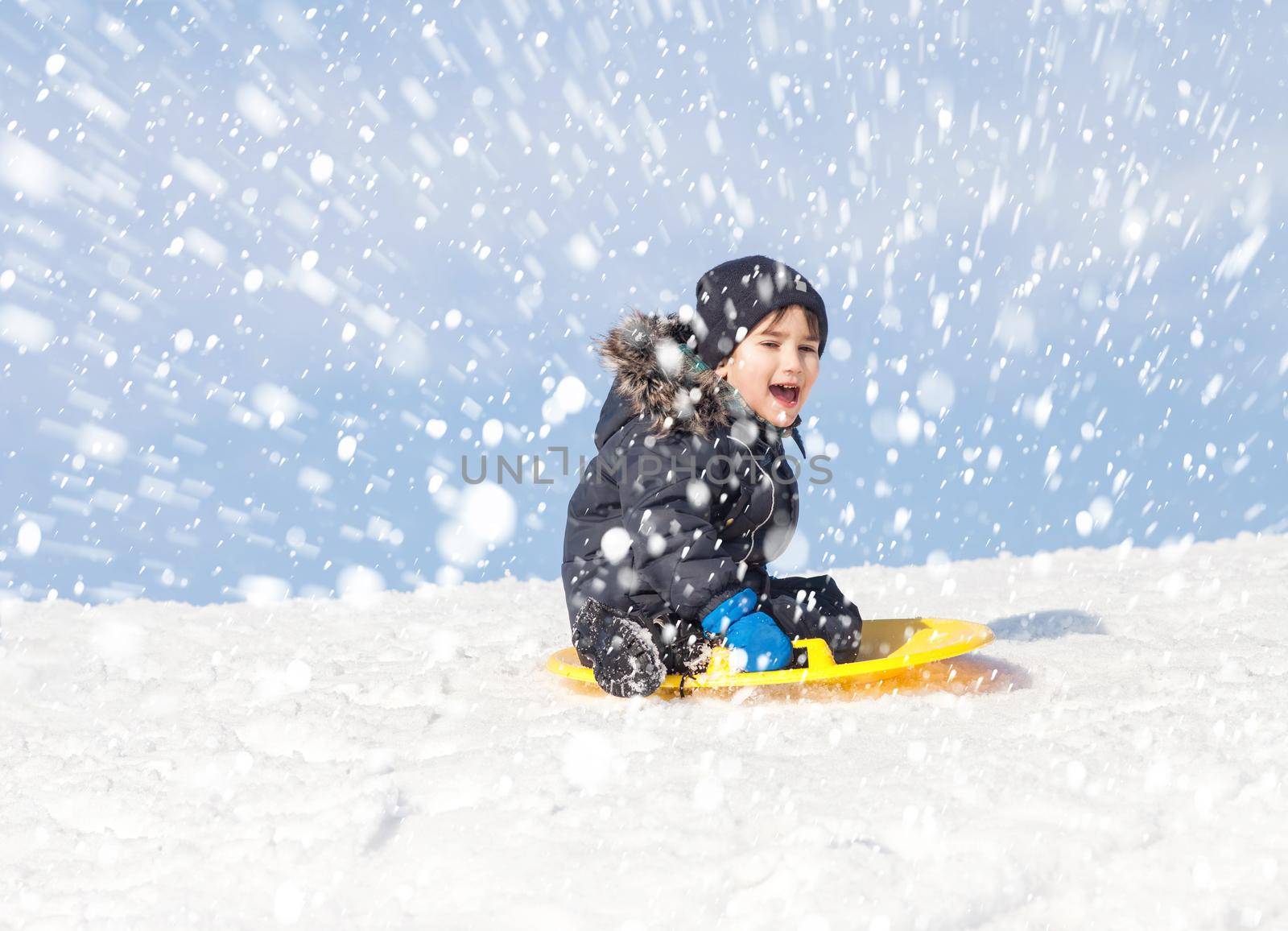 Boy on sleigh. Sledding during a snowfall on a winter day