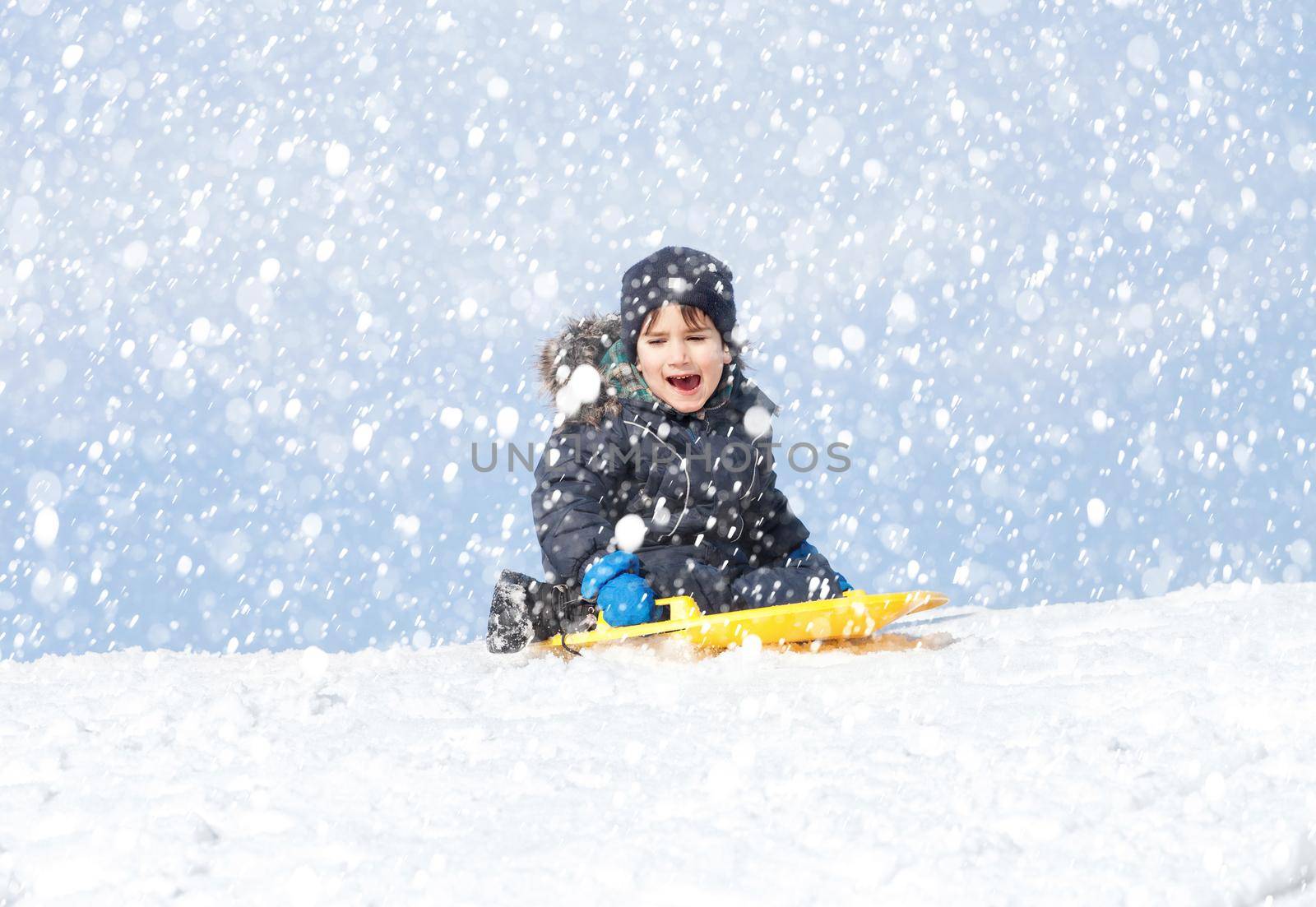 Boy on sleigh. Sledding during a snowfall on a winter day