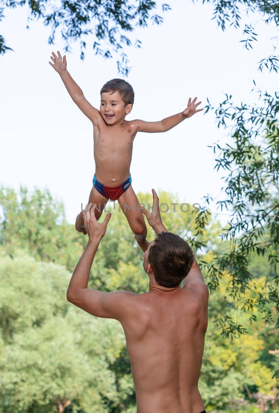 Happy childhood concept. Father throwing his child in the air. Loving father and his little son having fan together outdoors