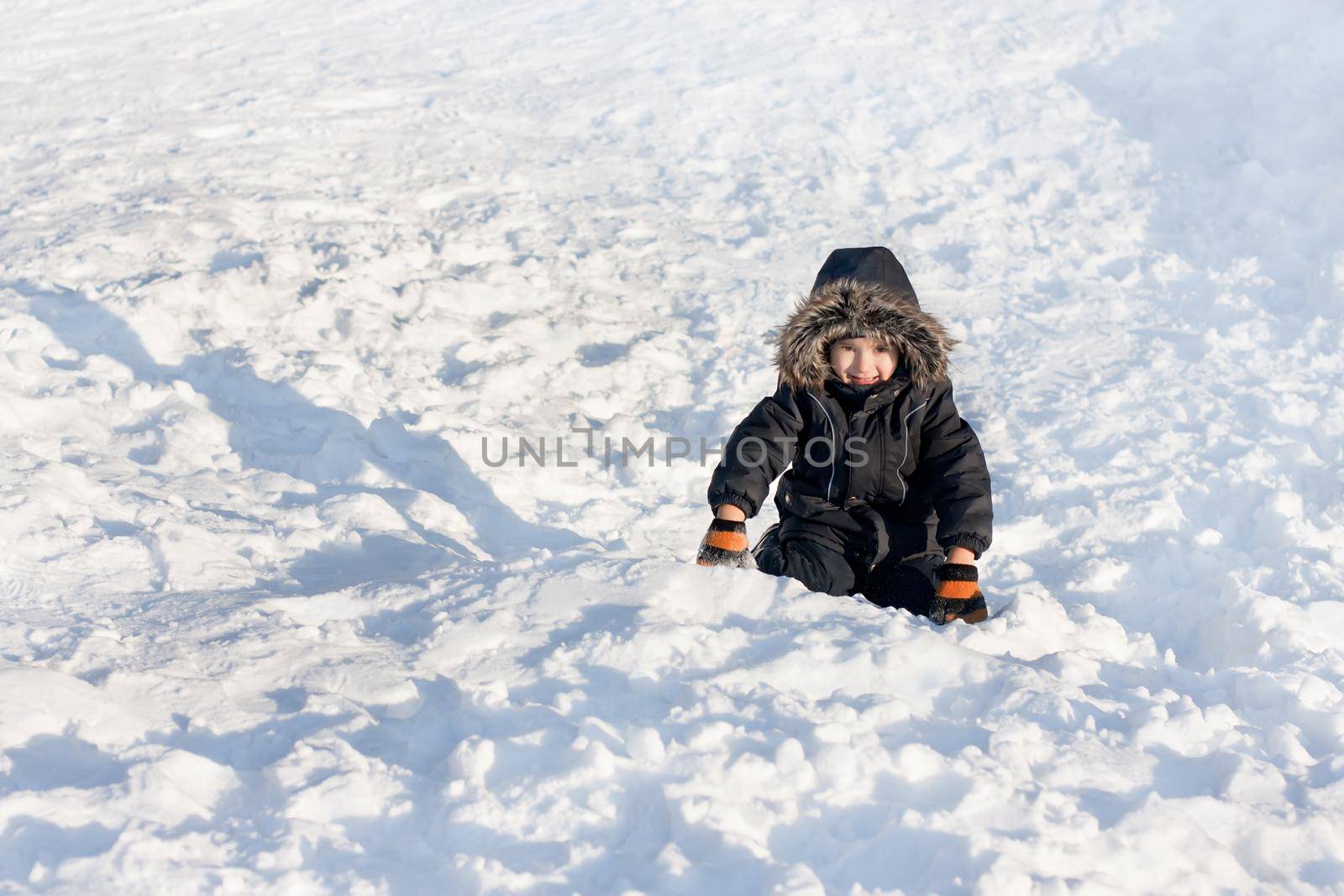 Young boy sitting on the snow by palinchak