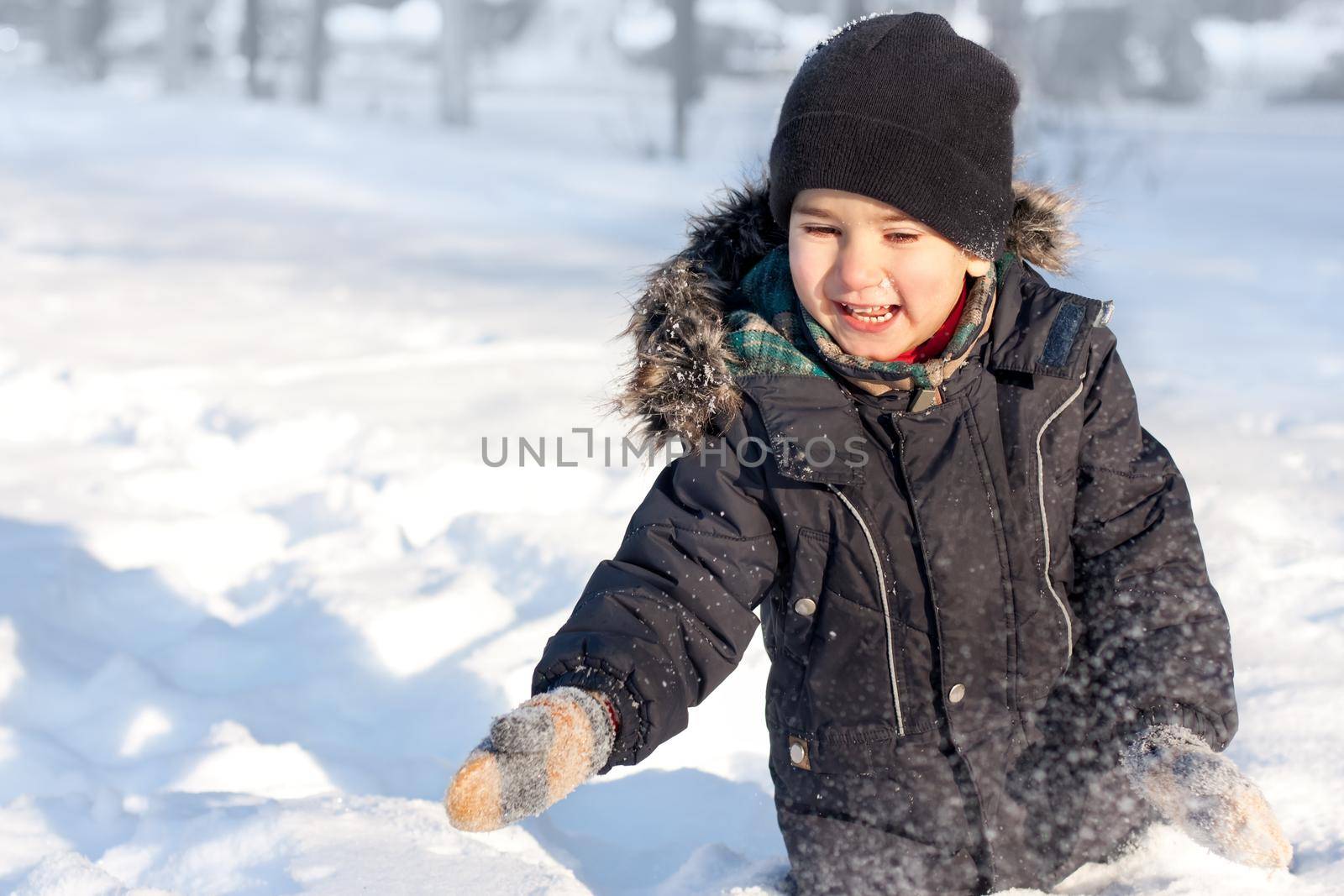 Winter portrait of laughing happy boy full of joy playing in snow