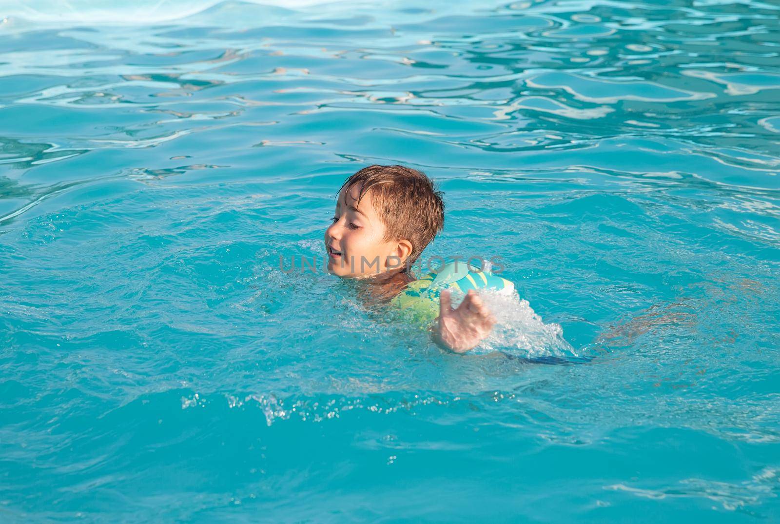 Little boy learning to swim in the pool 