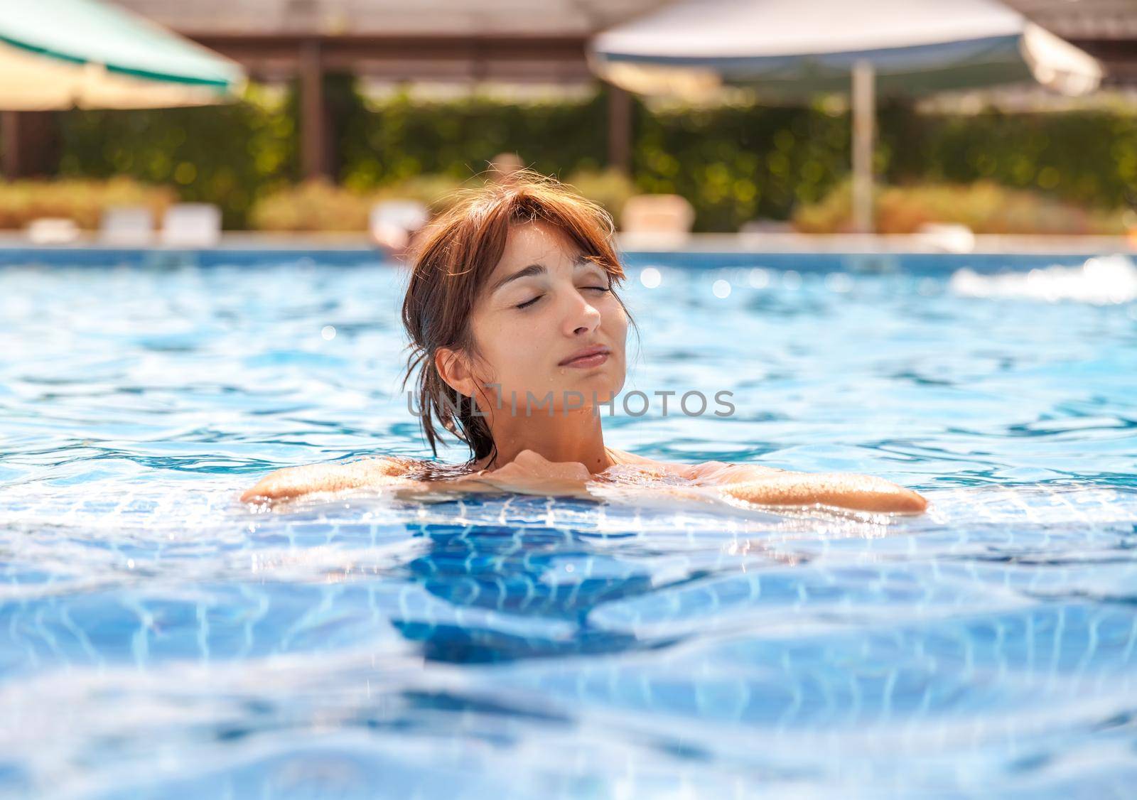 Portrait of a young woman with closed eyes relaxing in a swimming pool