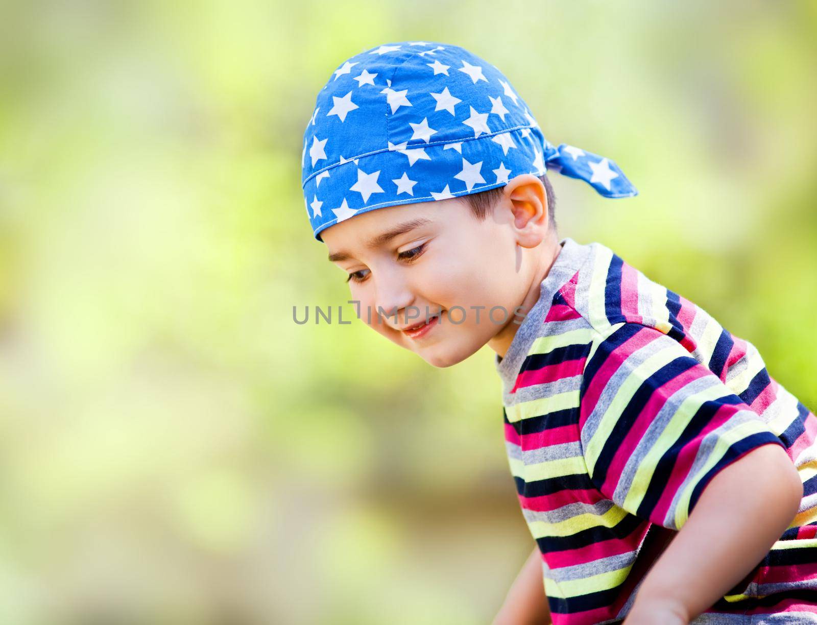 Happy cute young boy wearing bandana smiling outside portrait