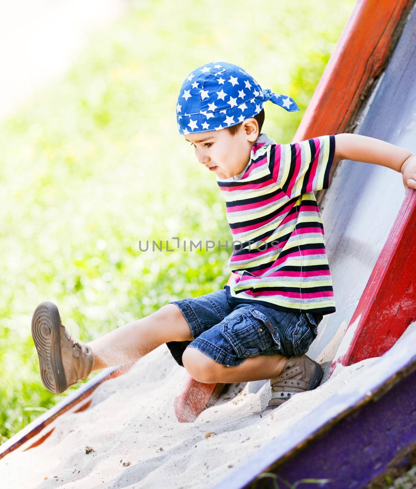 Cute boy in bandana playing on slide