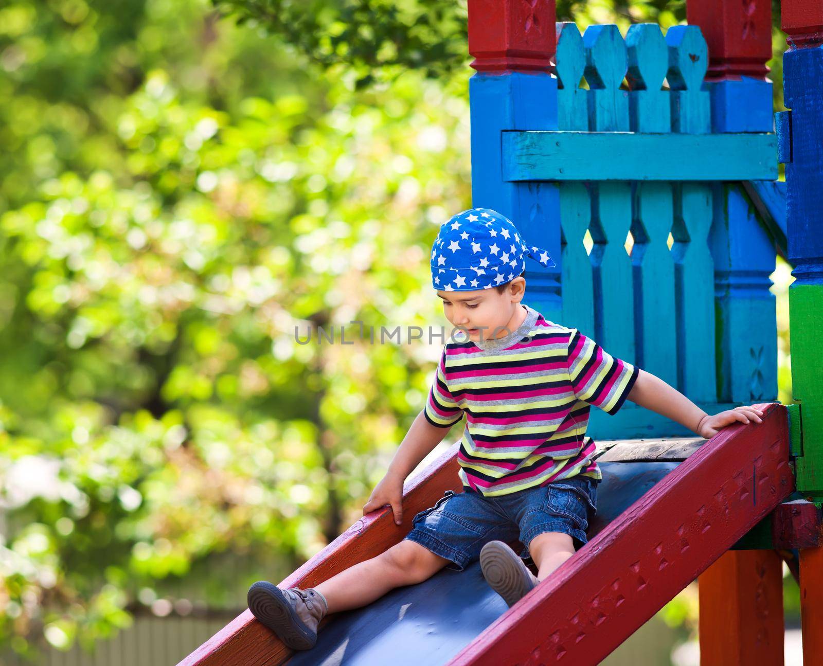 Cute boy in bandana playing on slide