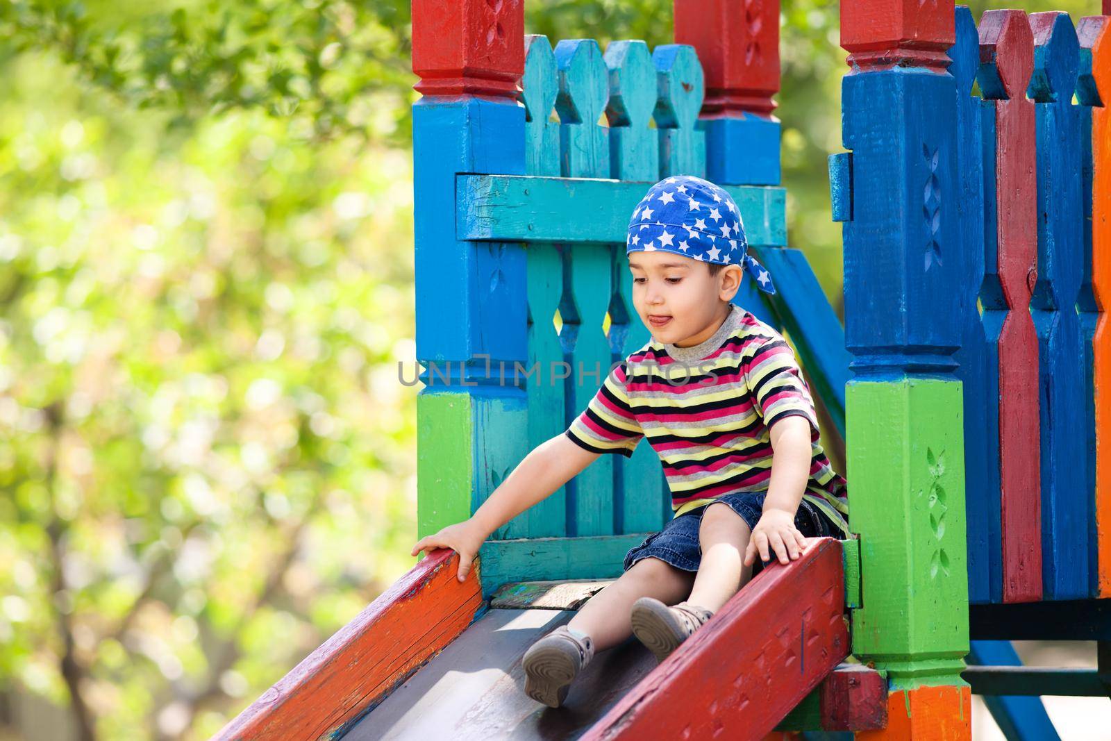 Cute boy in bandana playing on slide