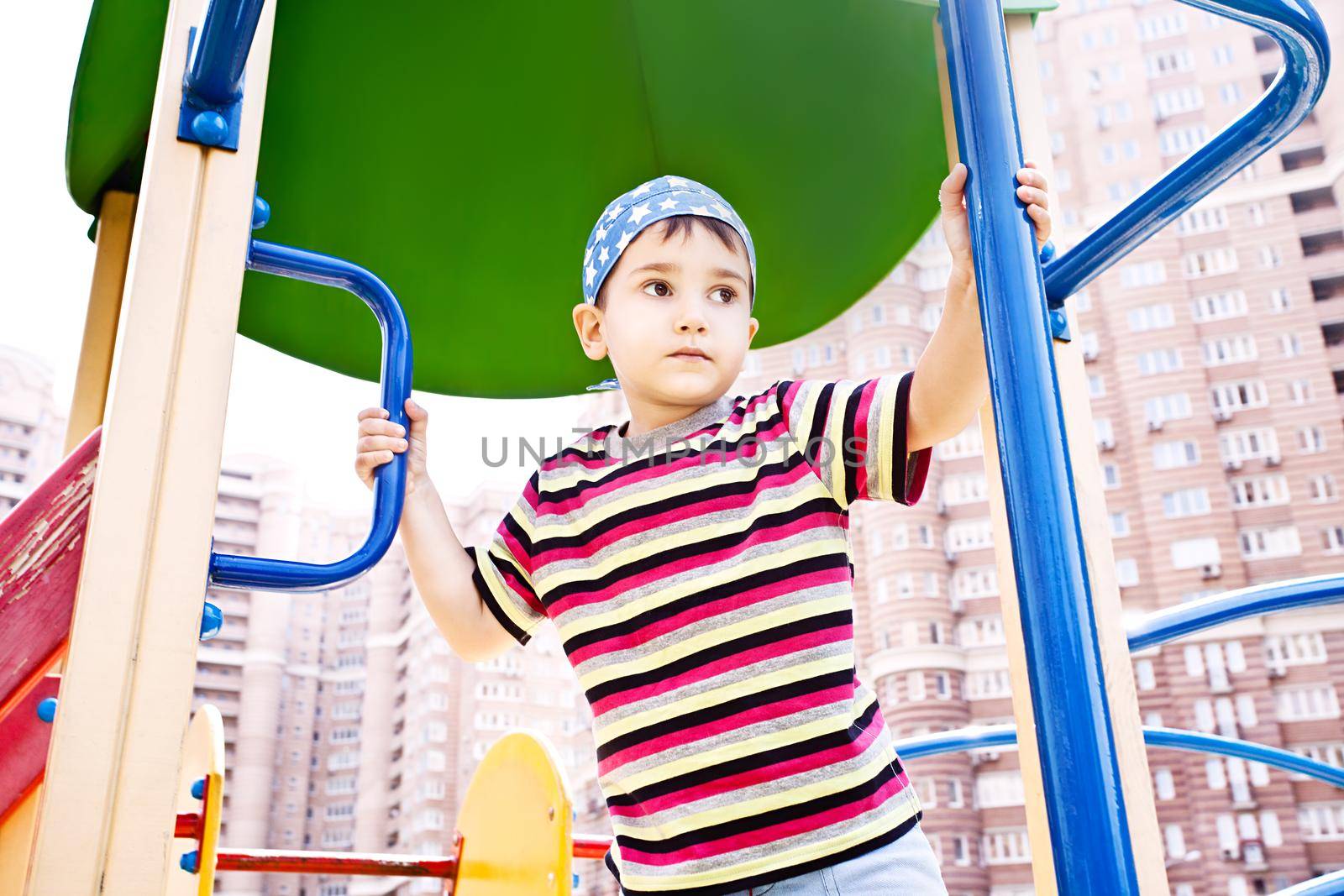 Young boy in bandana on playground  by palinchak