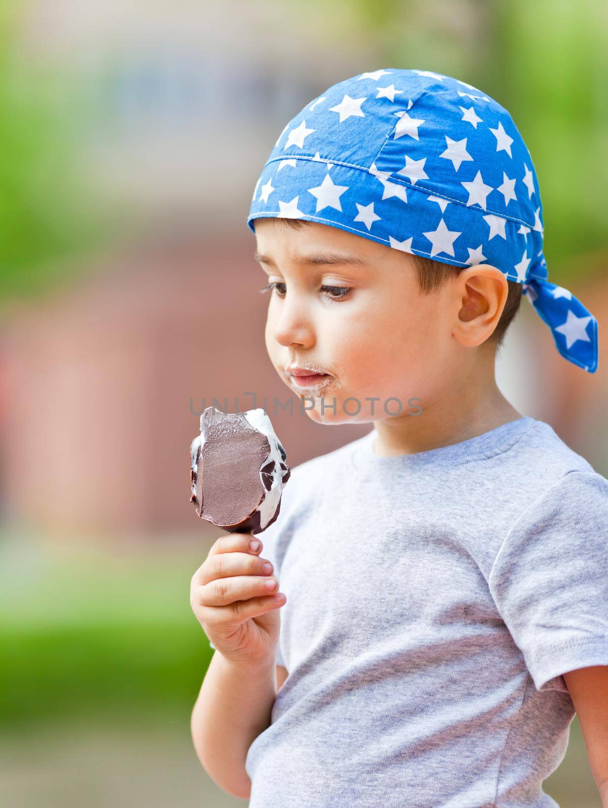 Cute little boy in bandana eats ice cream
