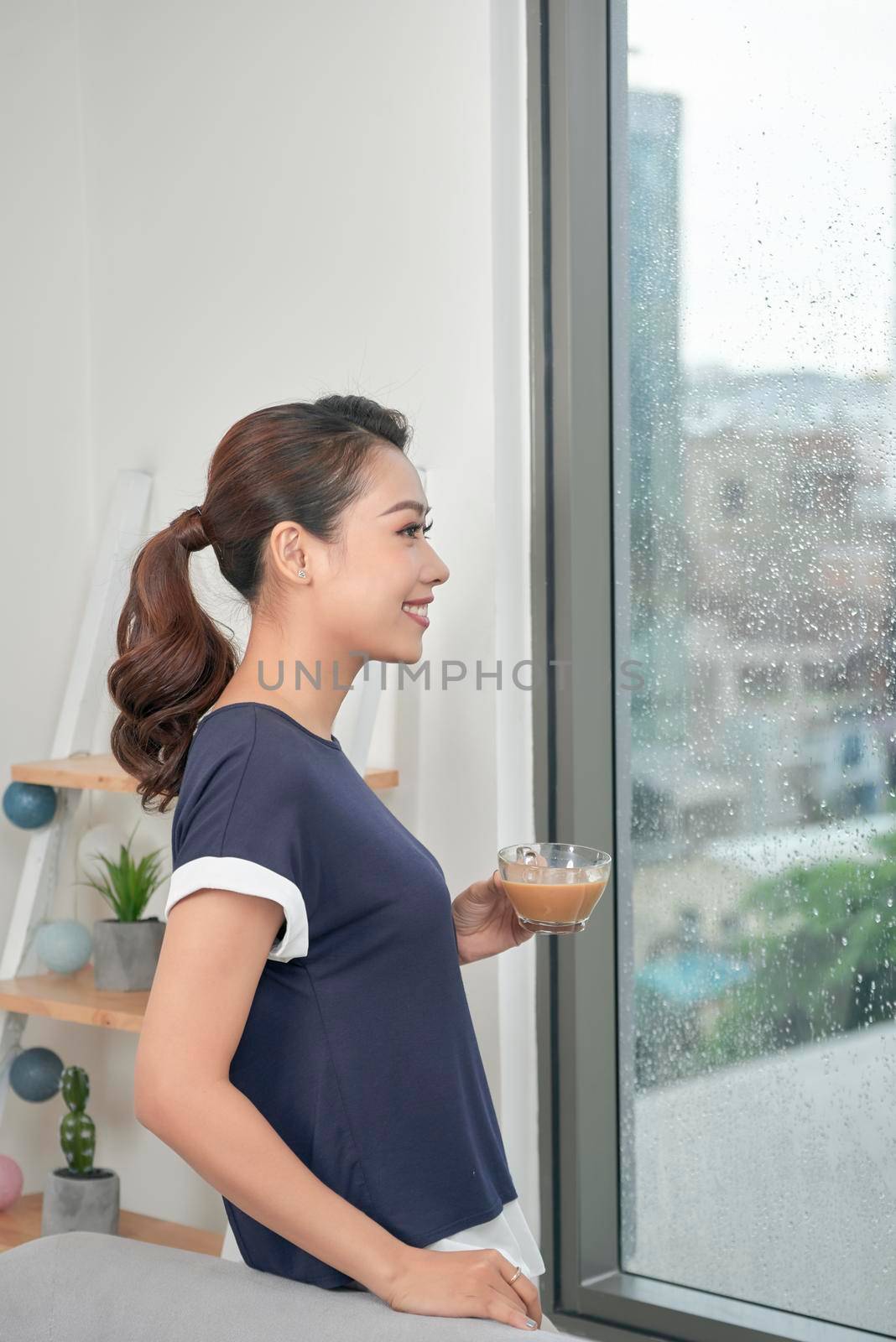 Attractive mixed female lifestyle enjoying a cup of tea looking out the window