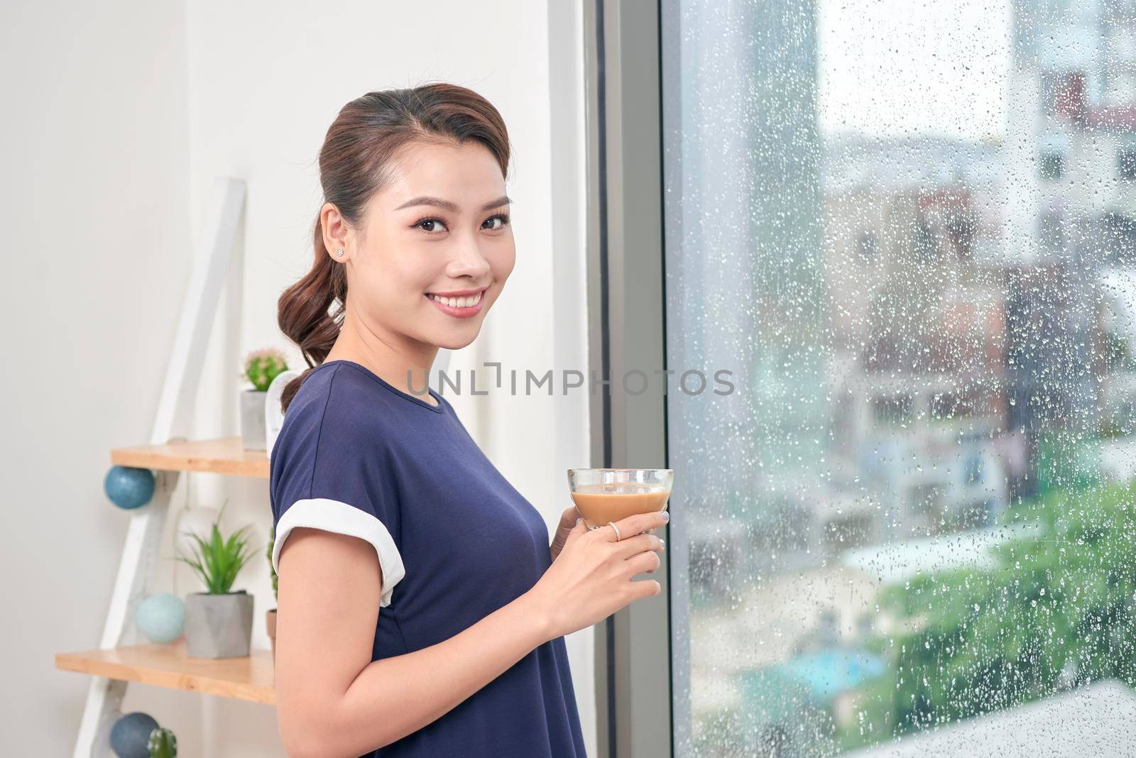 Attractive mixed female lifestyle enjoying a cup of tea looking out the window