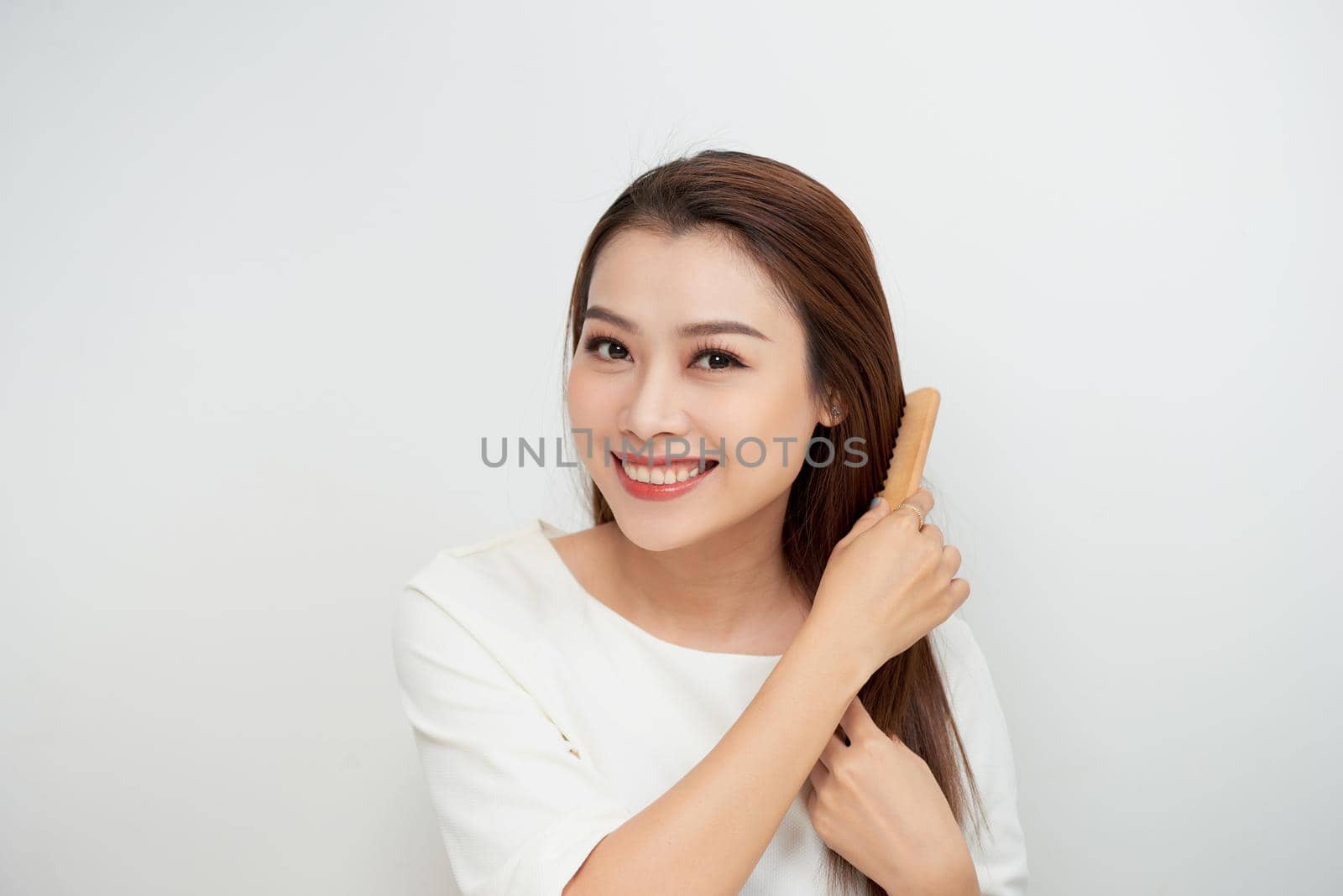 Isolated portrait of a beautiful young woman comb long hair