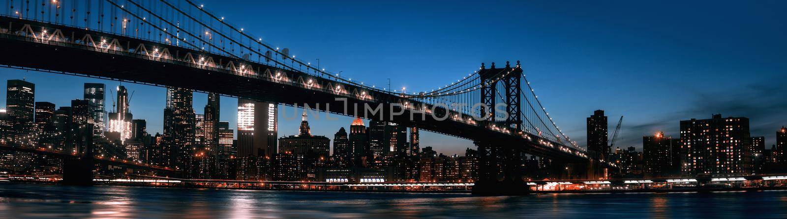 Manhattan skyline and Manhattan bridge silhouette at night. Manhattan bridge is a suspension bridge that crosses the East River in New York City. 