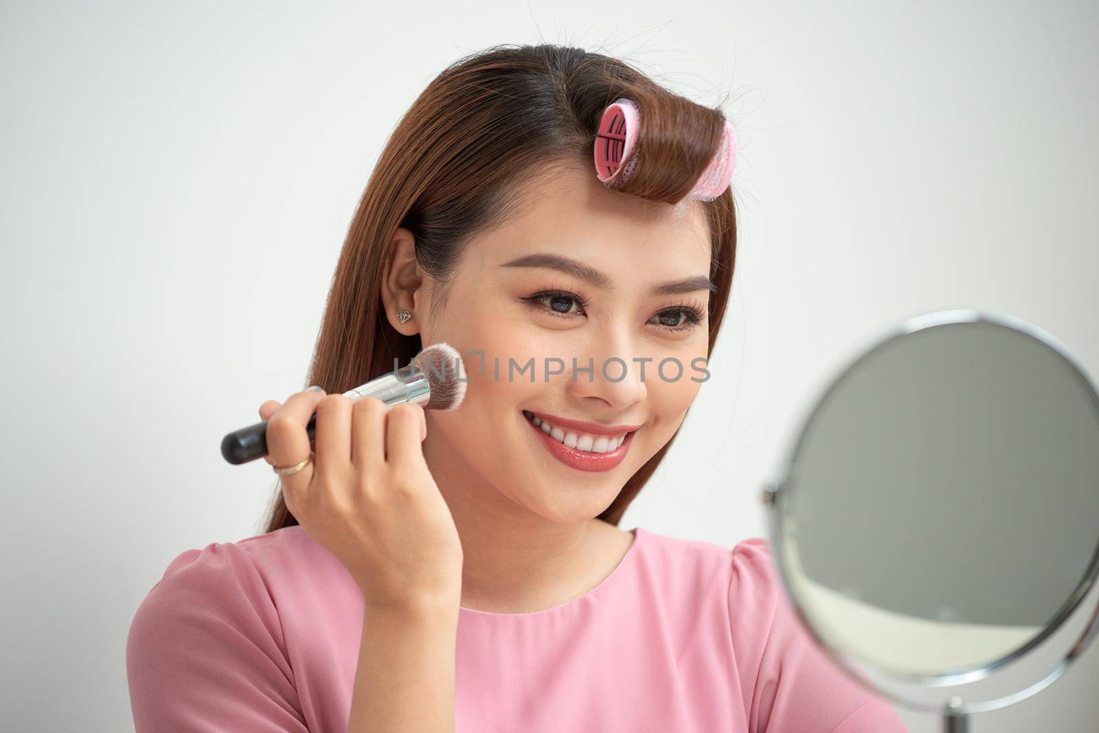 Gorgeous young brunette woman applying makeup by makidotvn