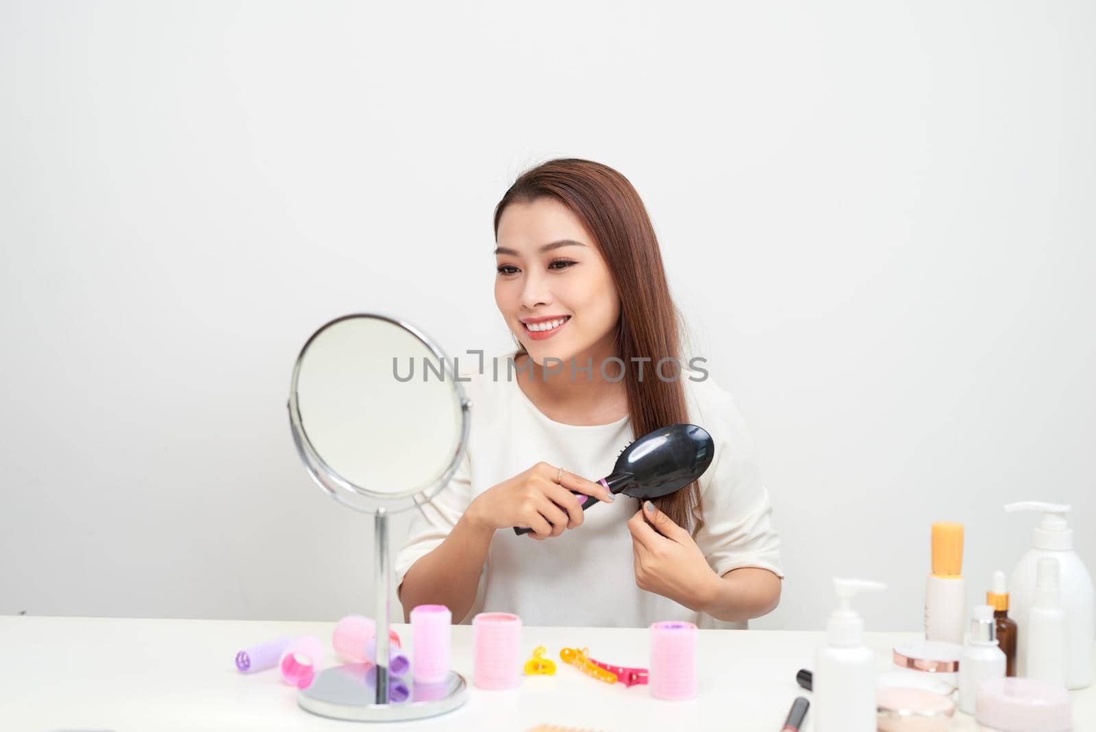 Getting rid of tangles. Beautiful young woman looking at her reflection in mirrorand brushing her long hair while sitting at the dressing table