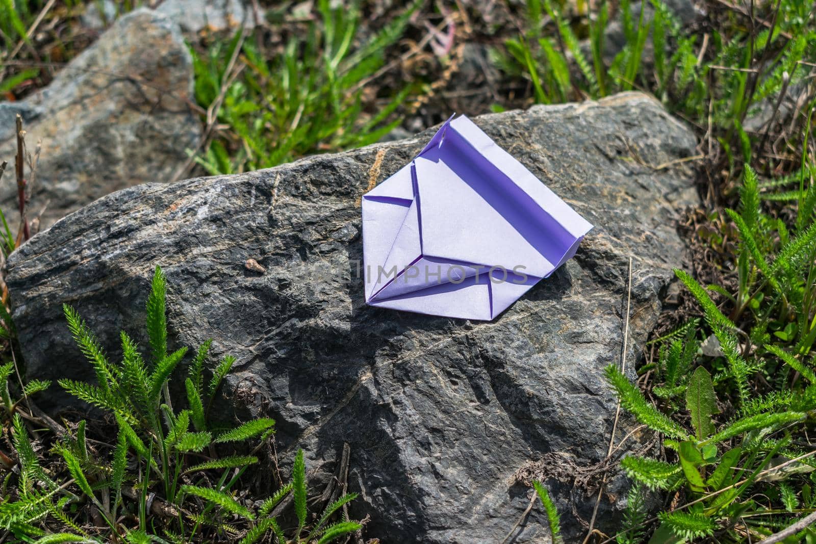 A hobby to do origami folding a car out of paper and put it on a stone in the grass in the summer in the bright sun