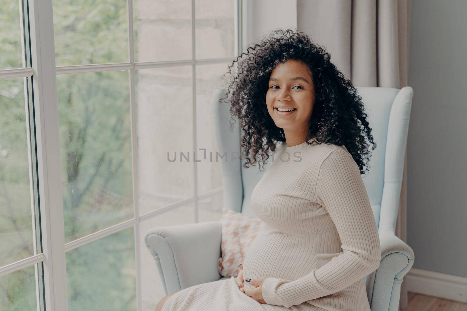 Happy afro american woman in white dress enjoying pregnancy by vkstock