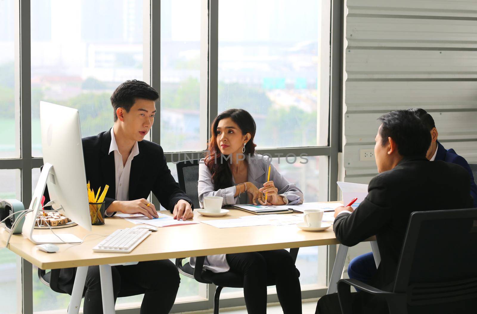 Shot of a group of businesspeople having a discussion in an office  by chuanchai