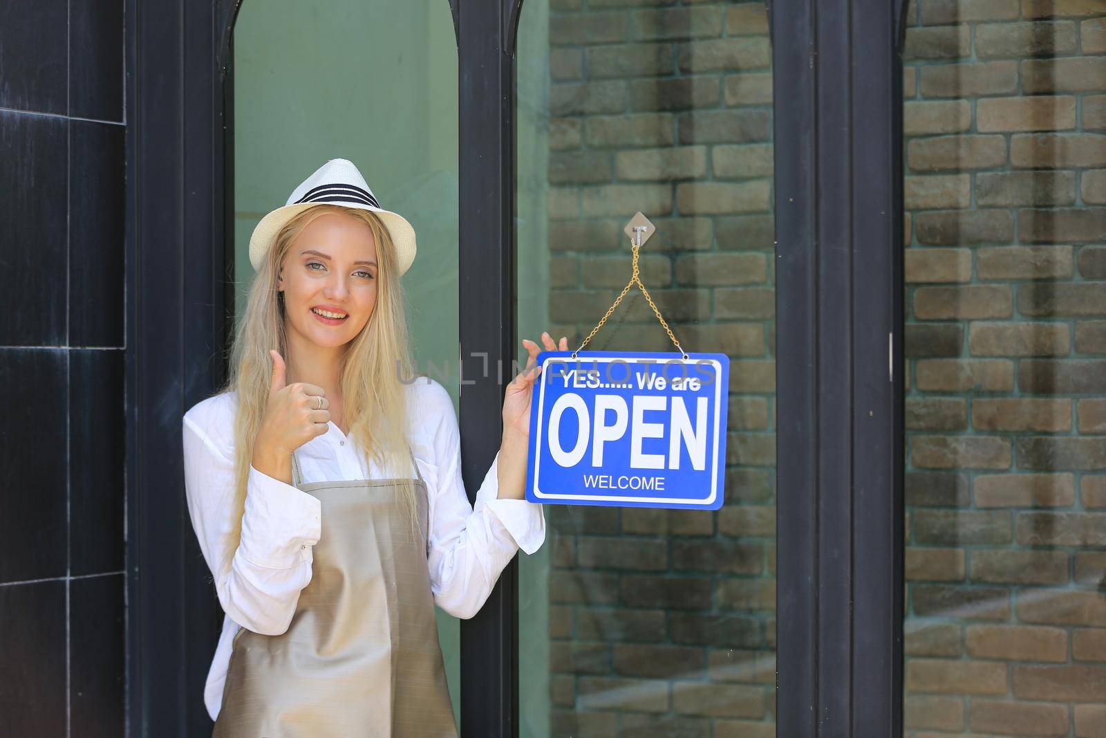 Portrait of confident young female shop, owner of small business coffee shop standing at shop front with open sign. by chuanchai