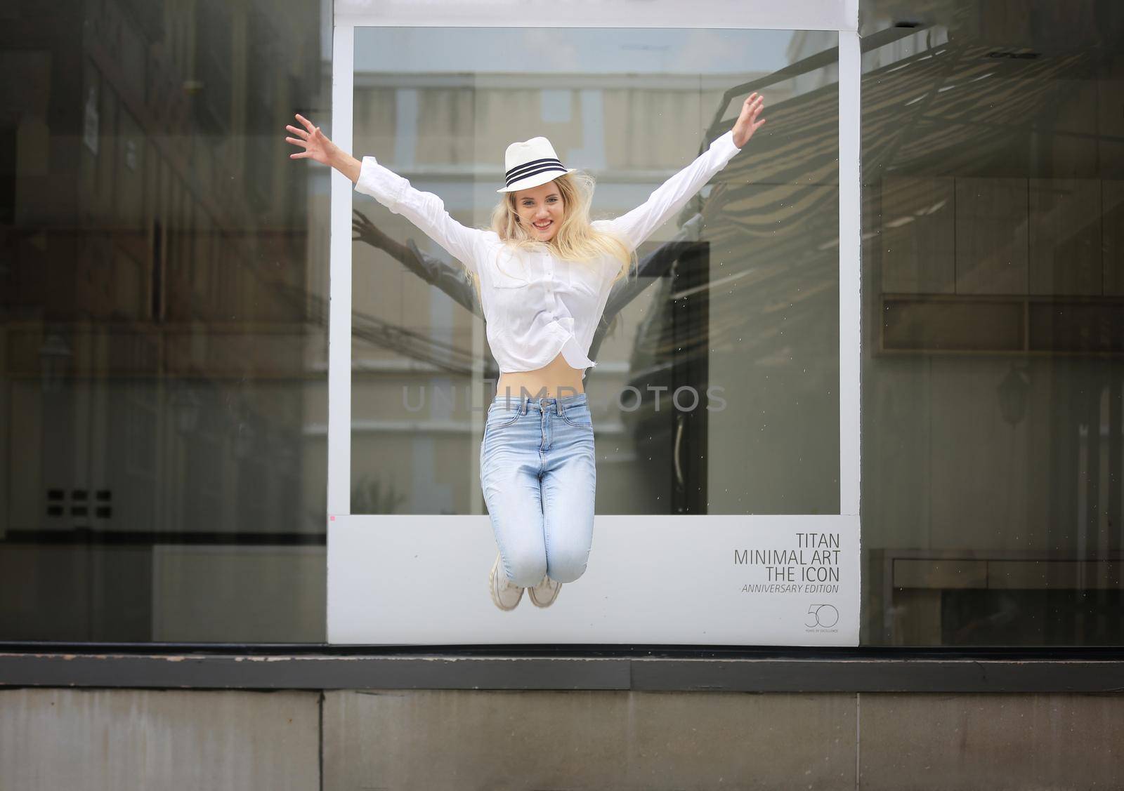 Beautiful blonde hair girl with white hat standing against wall glass as fashion pose outdoor.