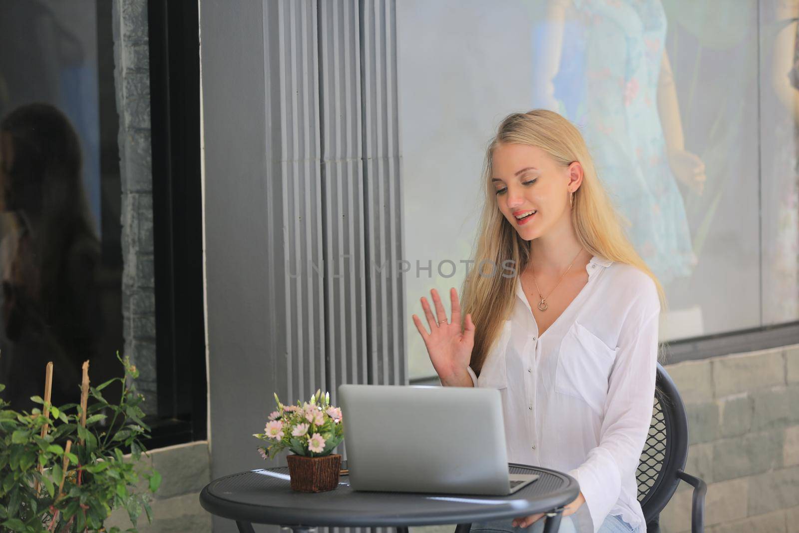 Beautiful blonde hair girl sitting with laptop in front of retails shop,Small business owner concept