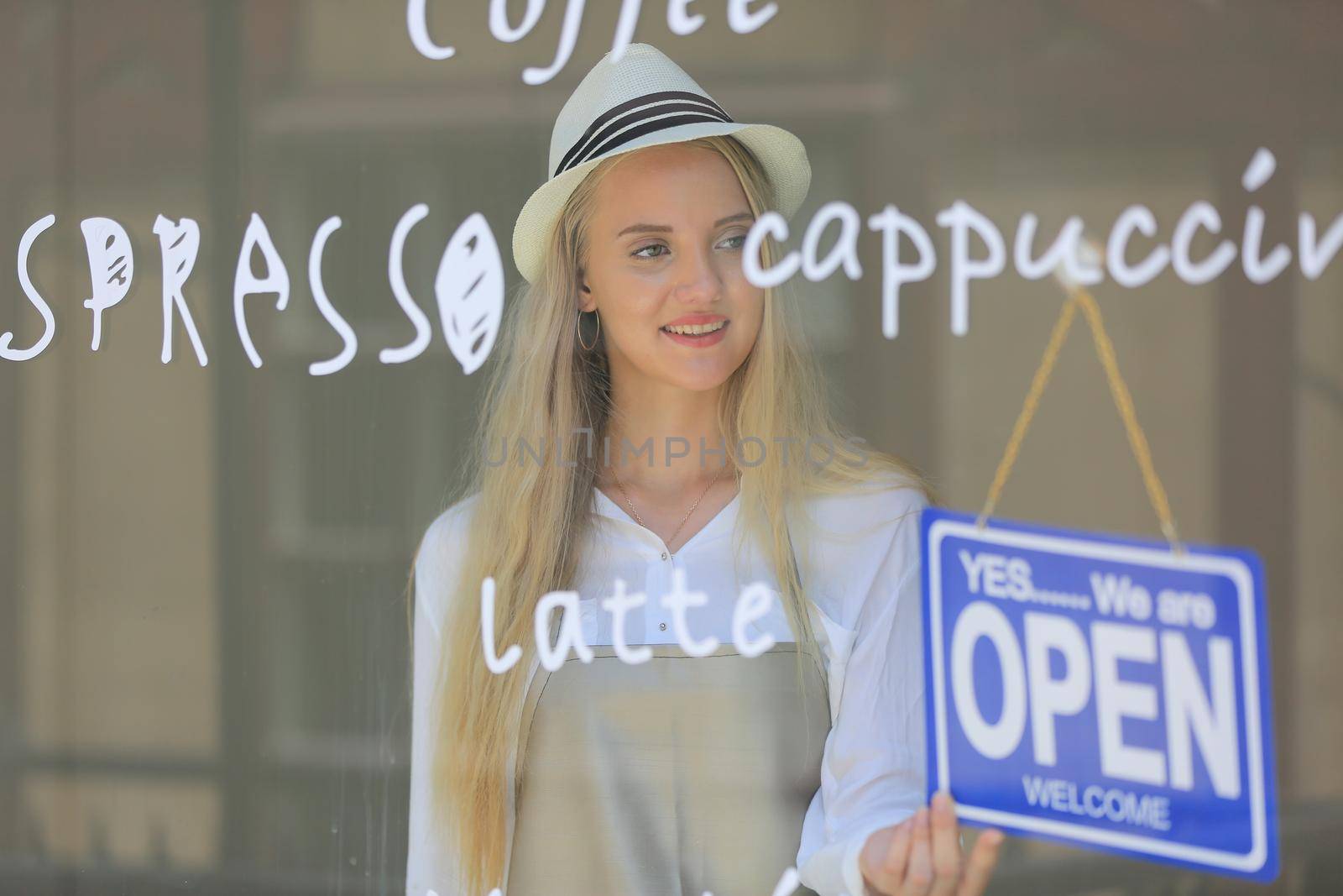 Portrait of confident young female shop, owner of small business coffee shop standing at shop front with open sign. by chuanchai