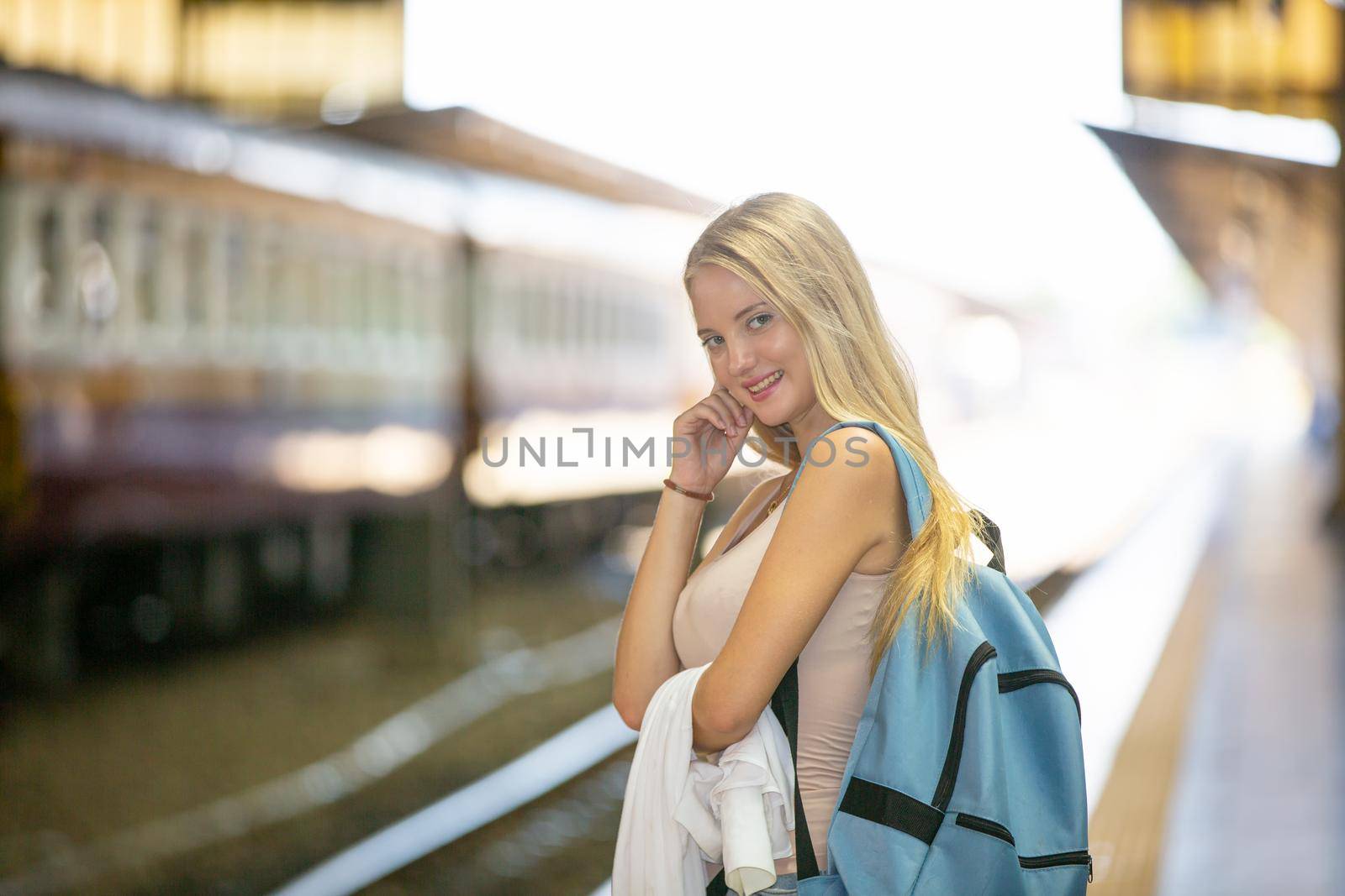 young woman waiting in vintage train, relaxed and carefree at the station platform in Bangkok, Thailand before catching a train. Travel photography. Lifestyle.