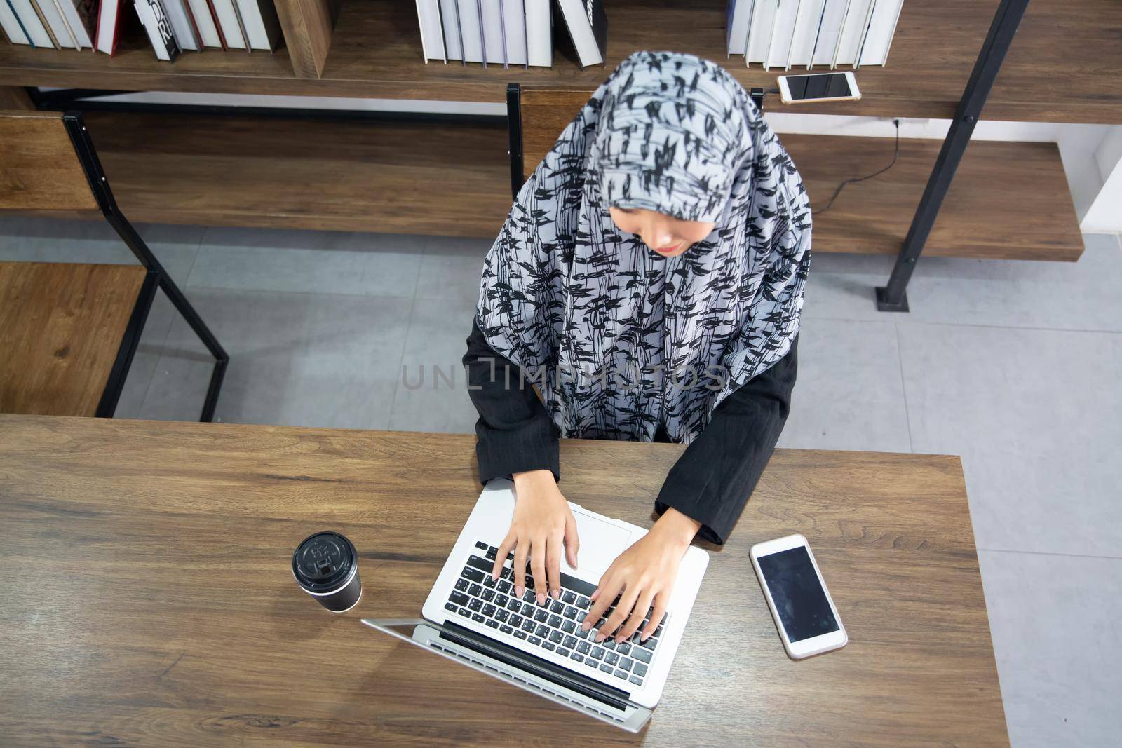 young Muslim woman using a laptop in a modern office by chuanchai