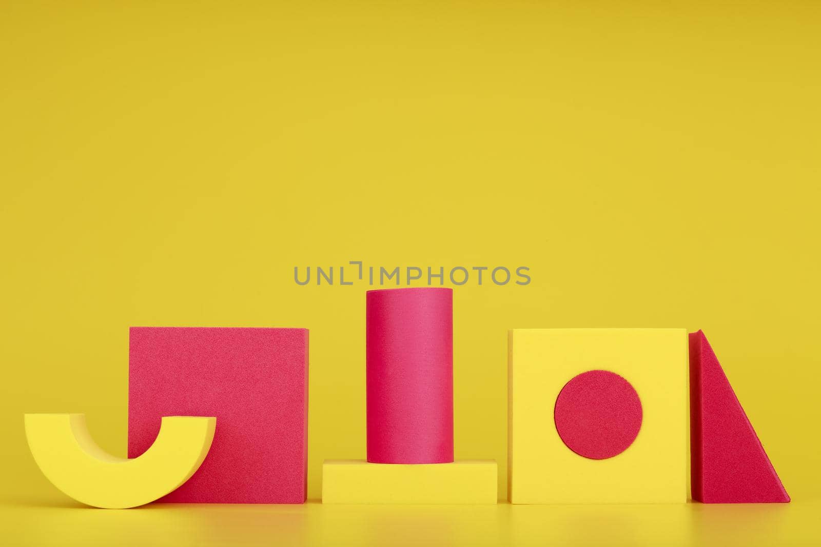 Creative duotone composition with yellow and pink geometric figures on yellow background. 