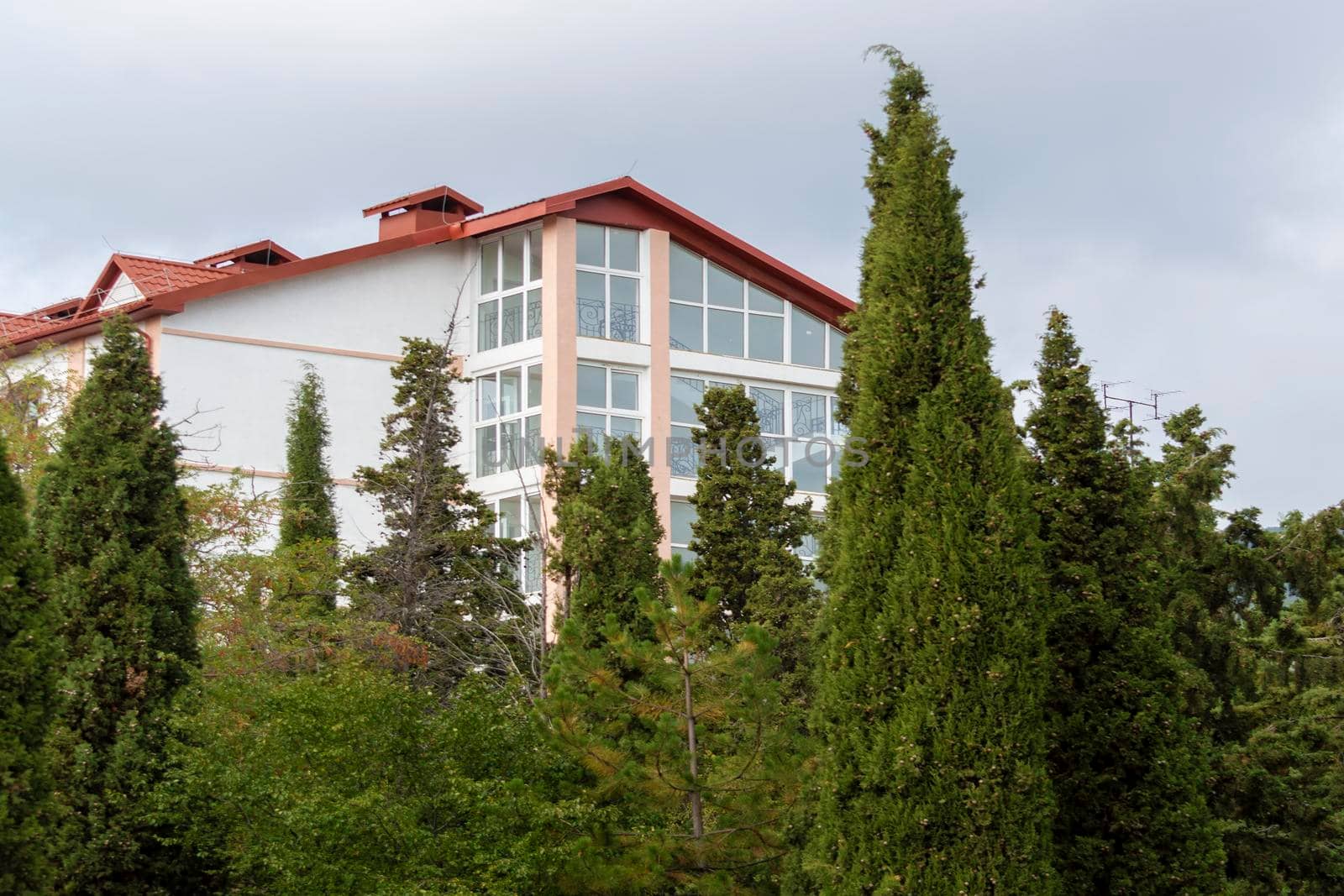 White building with panoramic windows behind trees. by Essffes