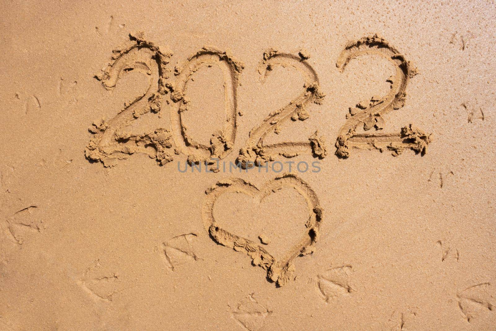 The numbers 2022 and the heart on the wet sand. The concept of the New Year 2022. Summer holidays and sea trips.