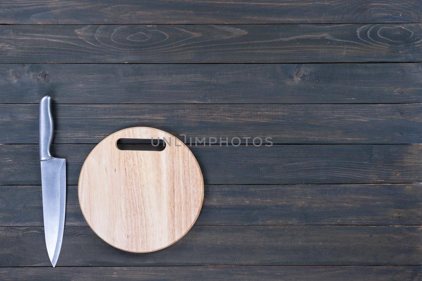 kitchen knife and wooden round empty cutting board on a wooden table close up