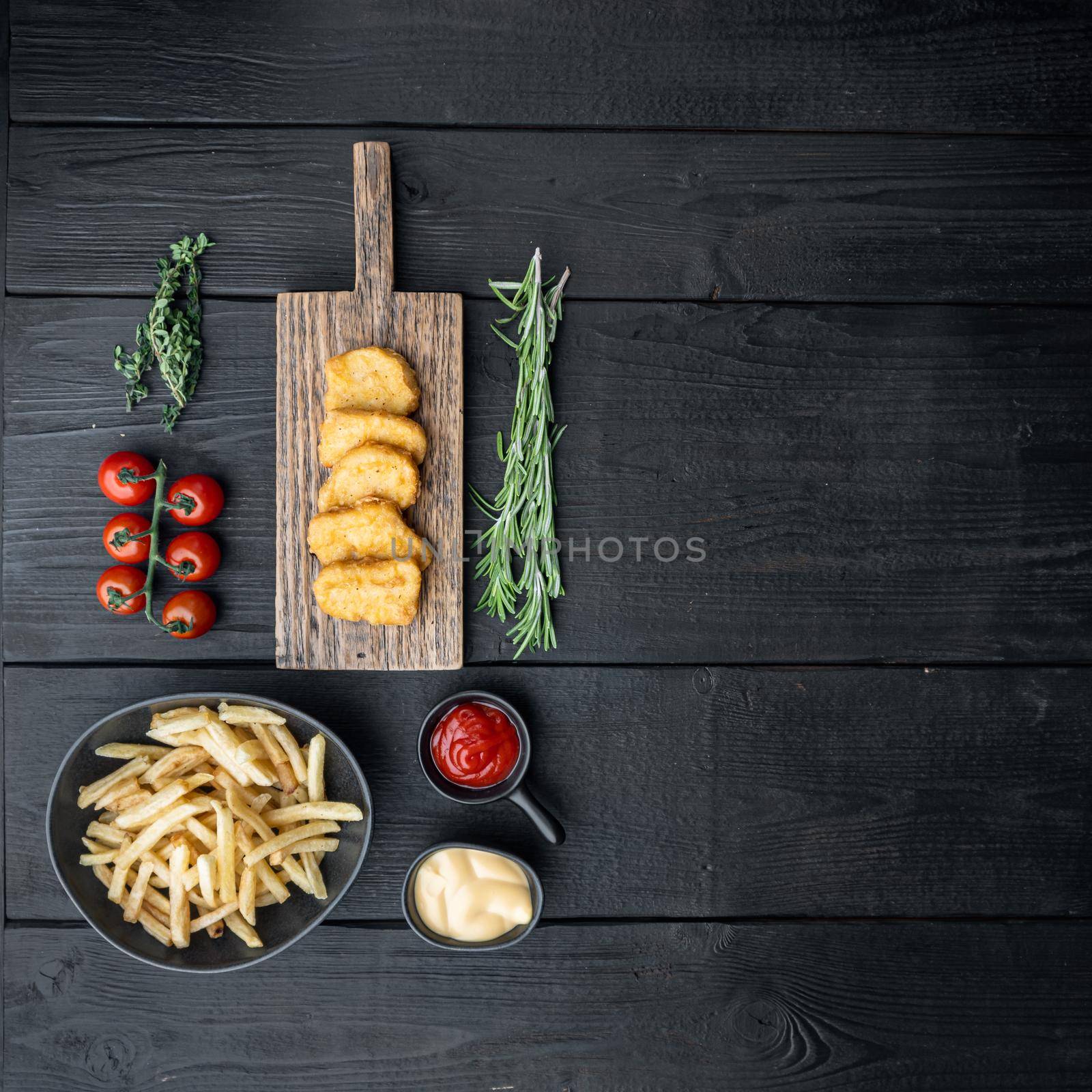 Crispy chicken nuggets on black wooden table, top view, with copy space by Ilianesolenyi
